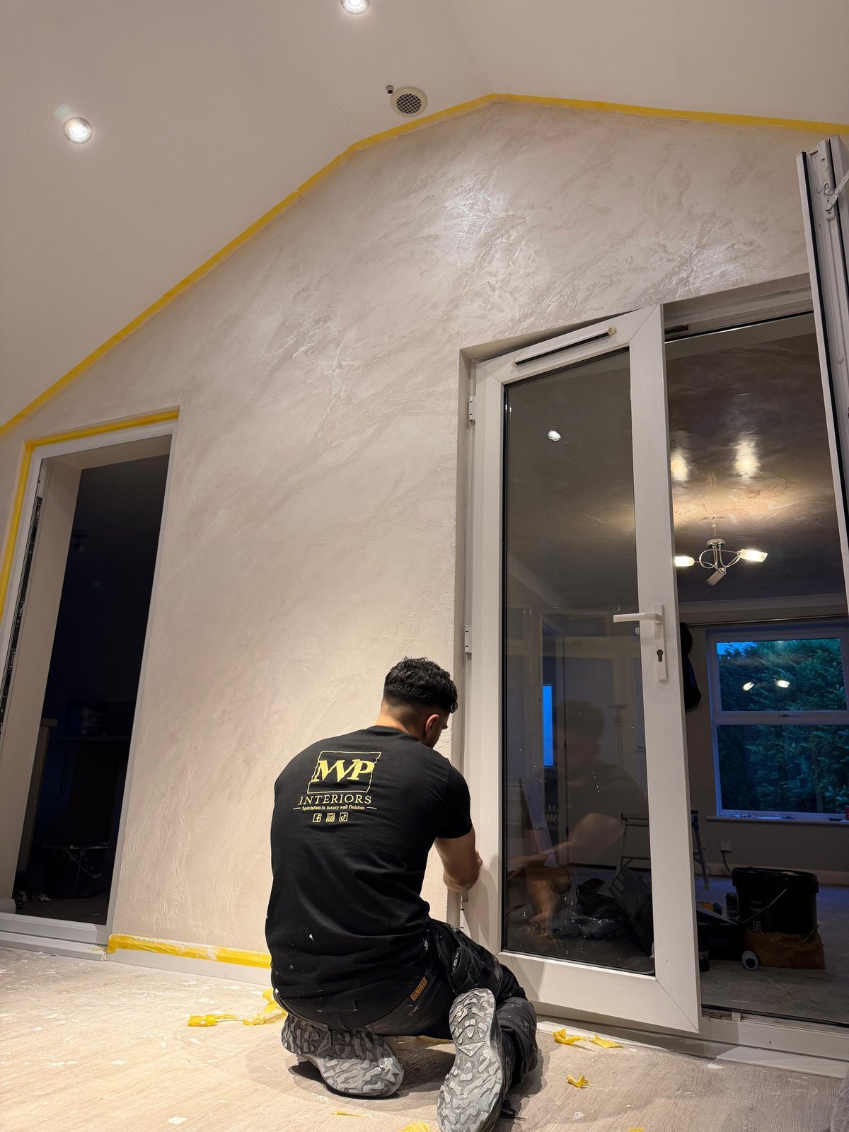 Craftsman applying Venetian plaster in an apex-roofed room