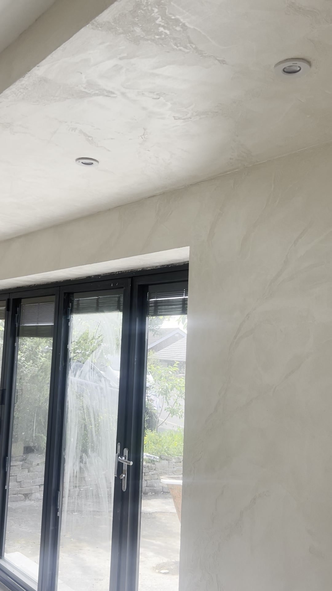 Seamless plaster finish across wall and ceiling beside bi-fold doors